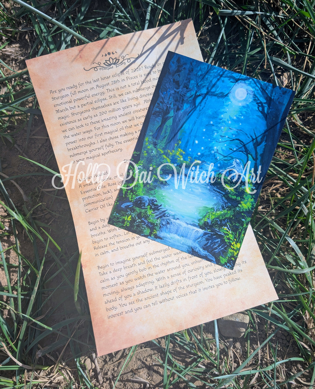 Two printed papers placed outdoors on grass. A ritual on a warm beige background parchment paper and a print of a river scened illustration.